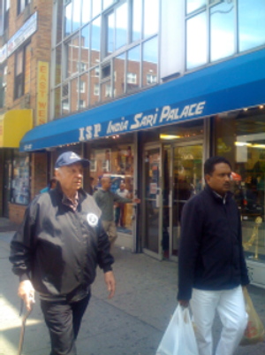 Customers walking along the street on a typical afternoon in Jackson Heights. The Sari Palace in the background is a popular clothing shop which specializes in wedding garments. This store attracts both South Asian and non-South Asian customers.