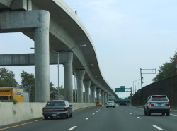 An elevated rail line follows the centerline of Interstate 678 between 94th Avenue and JFK International Airport in Southeast Queens.
