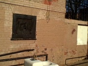 A closeup of the side of the field house, with peeling paint, broken bricks, and loose wiring. Photo credit: dg